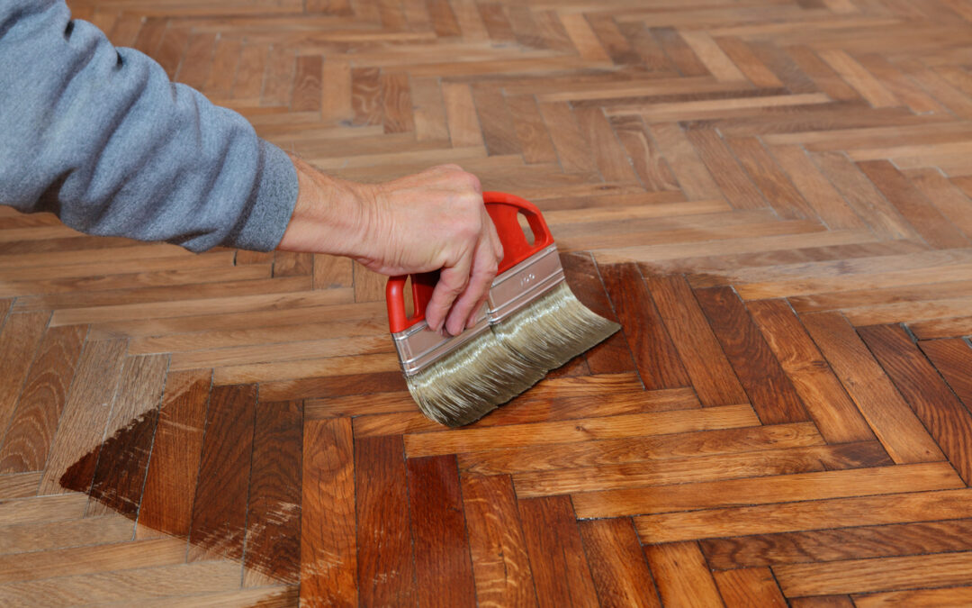 Parket vernissen: een expert werkt de houten vloer na het schuren af met vernis